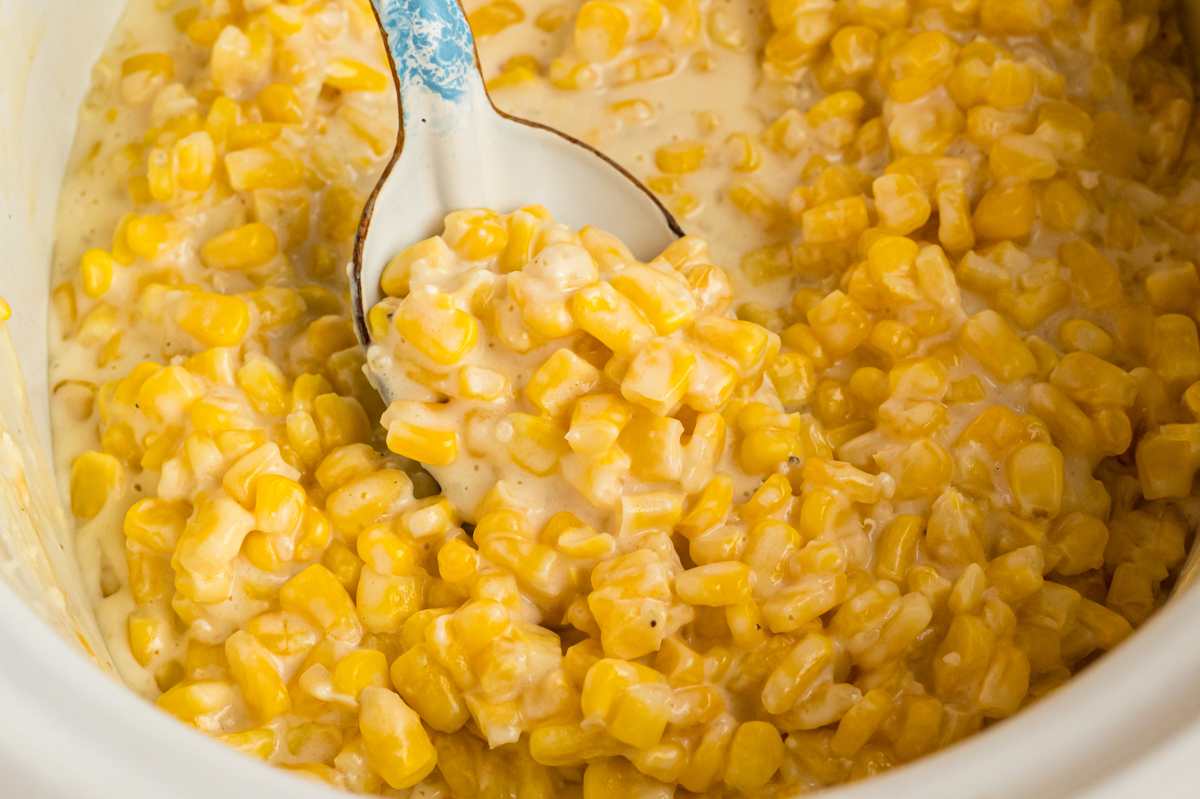 Slow cooker honey butter corn with a spoon in it.