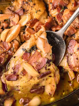 A spoon picking up a piece of slow cooker 40 clove chicken.