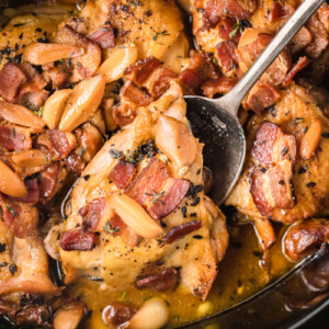 A spoon picking up a piece of slow cooker 40 clove chicken.