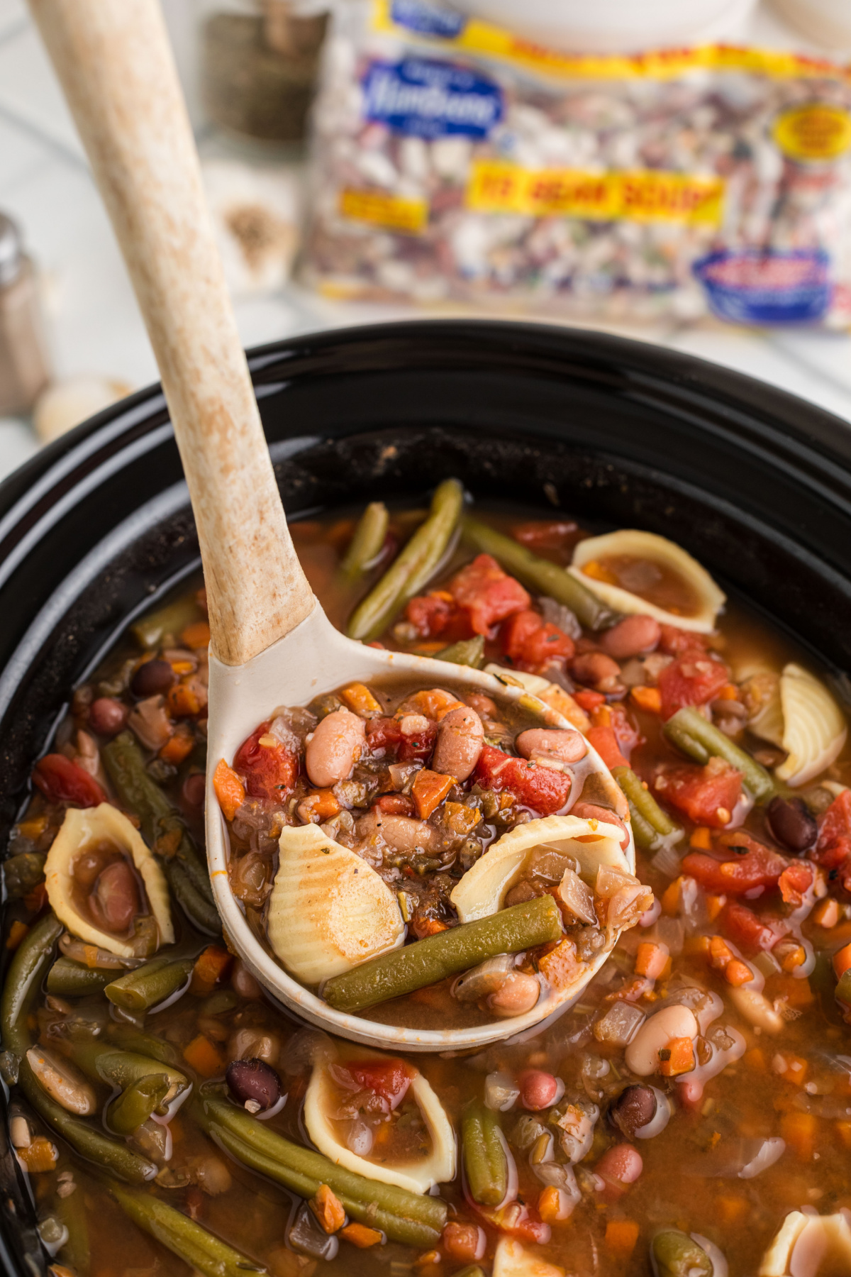 Minestrone 15 bean soup in a slow cooker with ladle.