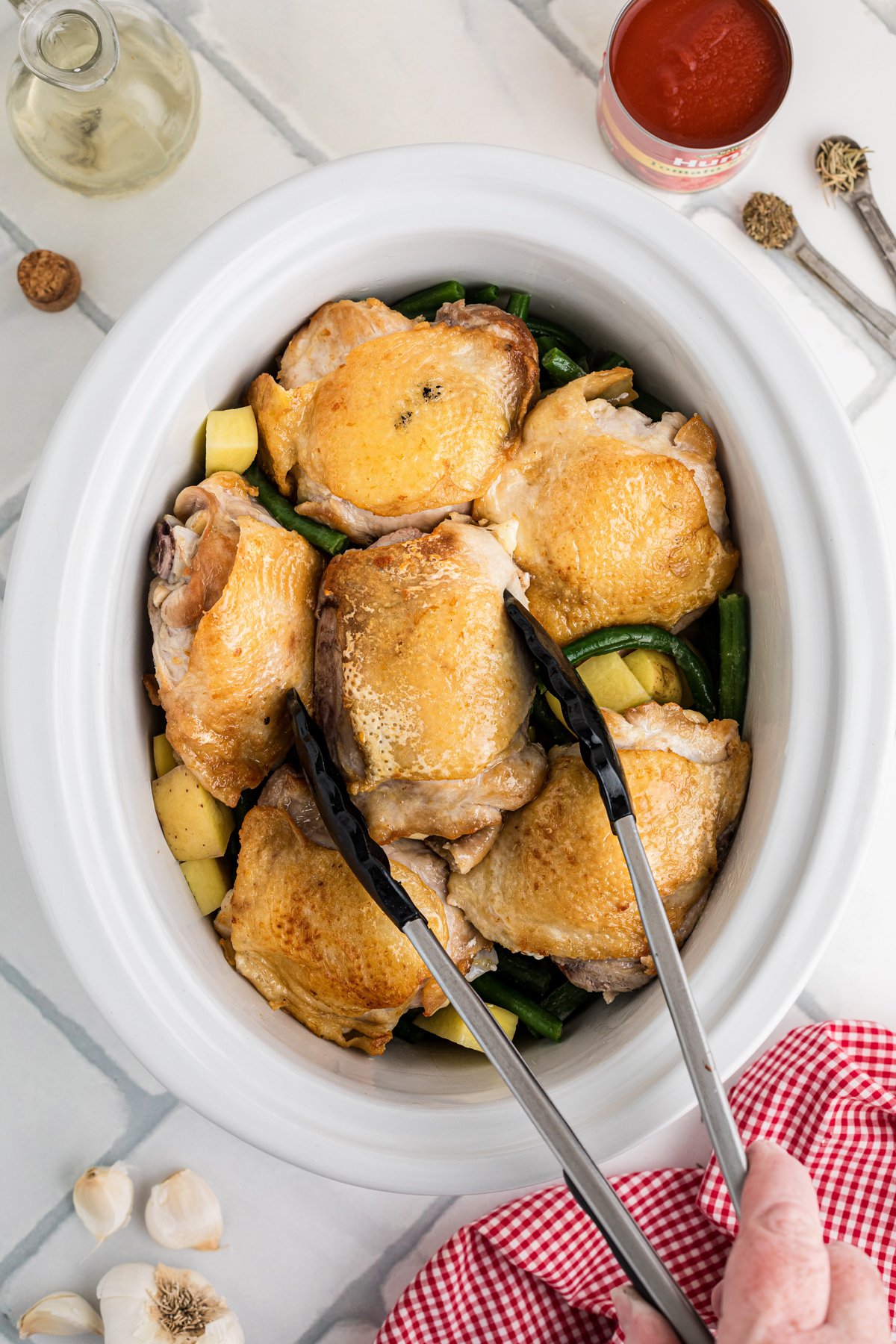Seared chicken thighs added to green beans and potatoes in a crockpot.