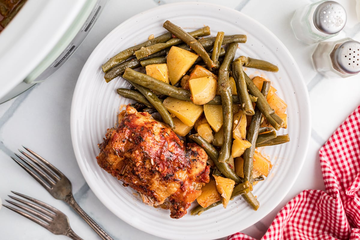 Slow cooker full chicken dinner on a white plate.