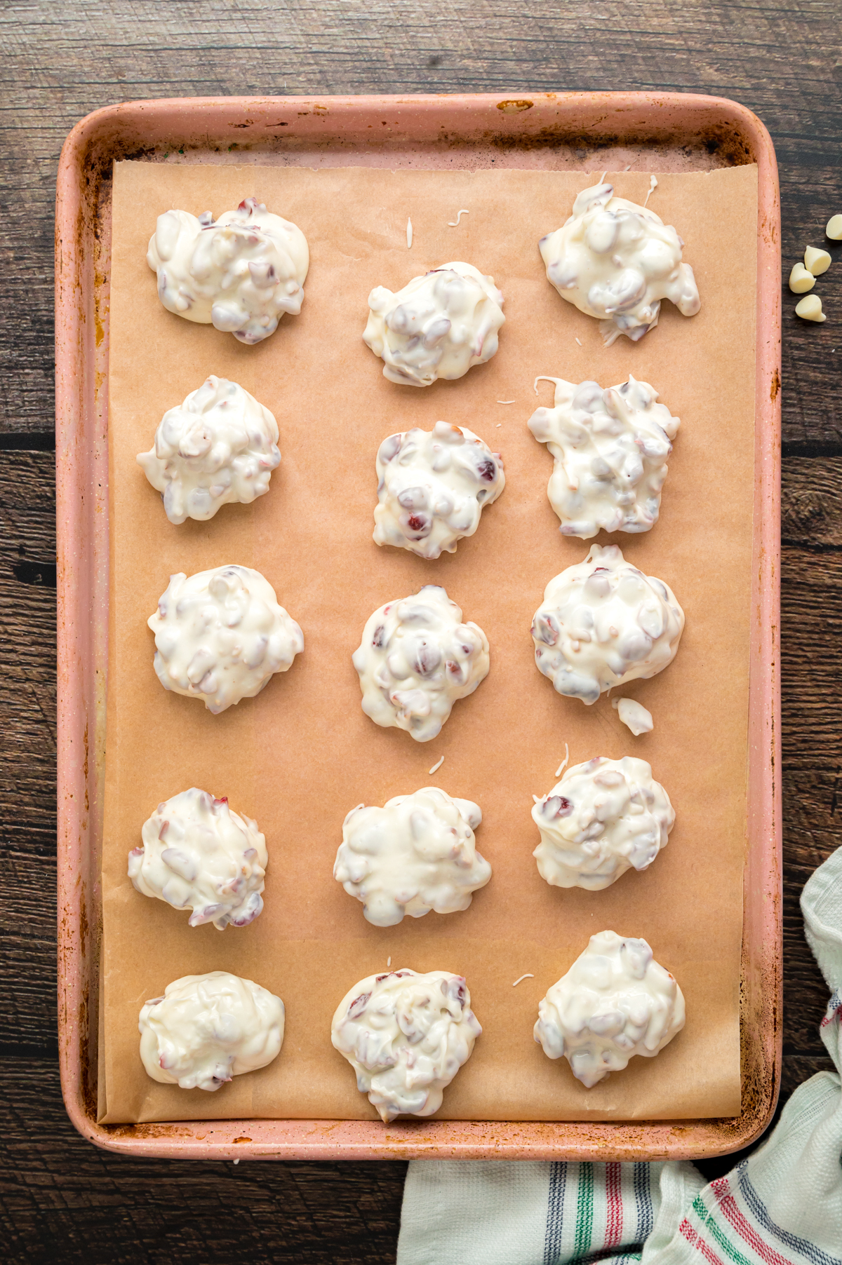 White chocolate clusters dropped onto a parchment-lined baking sheet to set.