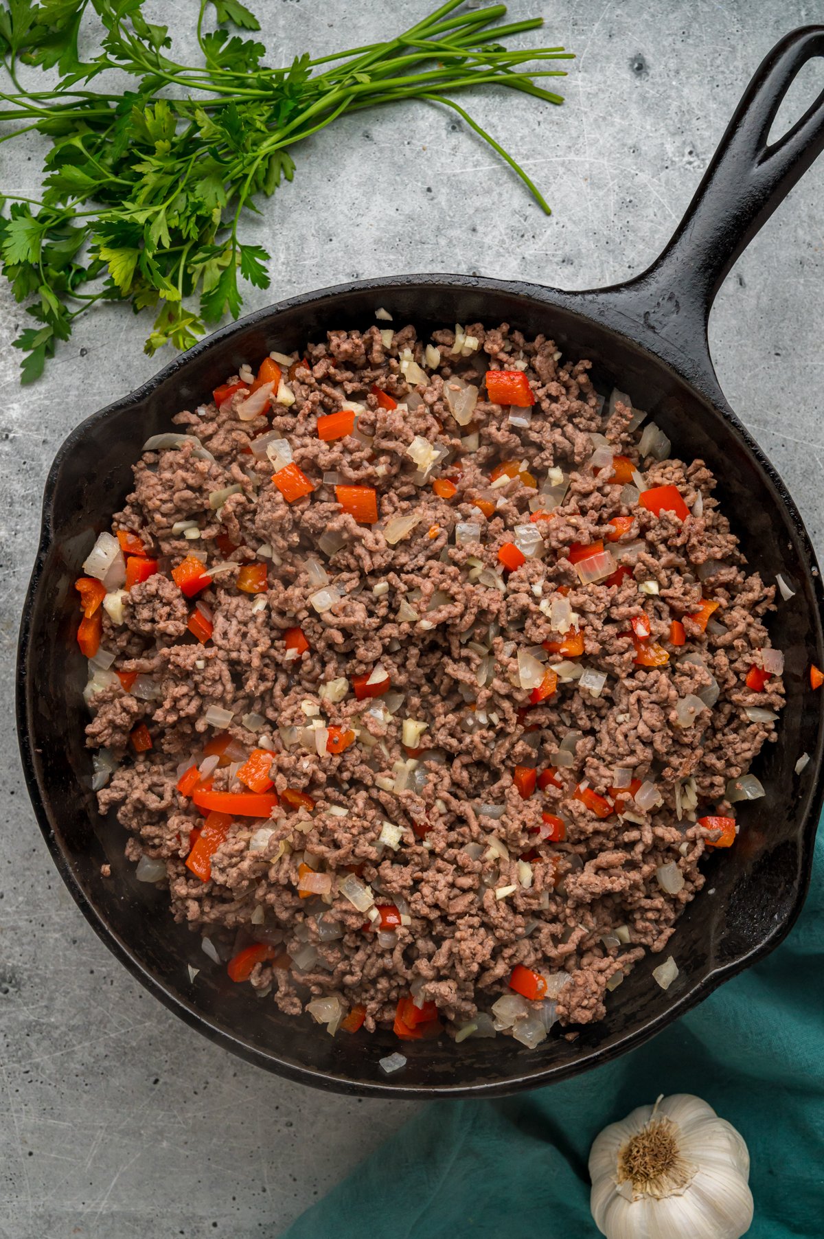 Cooked ground beef with peppers, onions, and garlic in a skillet.
