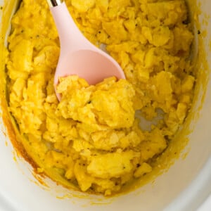 A spoon scooping out some slow cooker scrambled eggs.