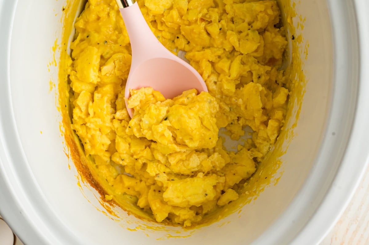 A spoon scooping out some slow cooker scrambled eggs.