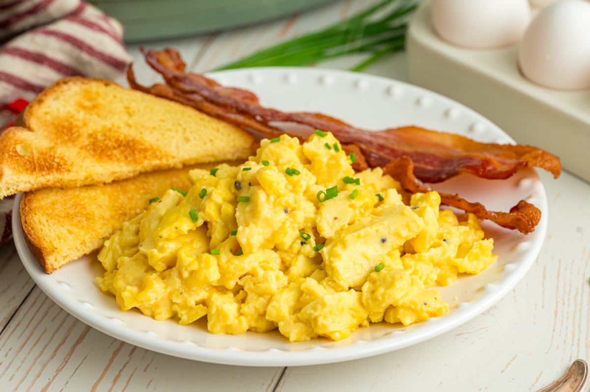 Slow cooker scrambled eggs, toast, and bacon on a plate.