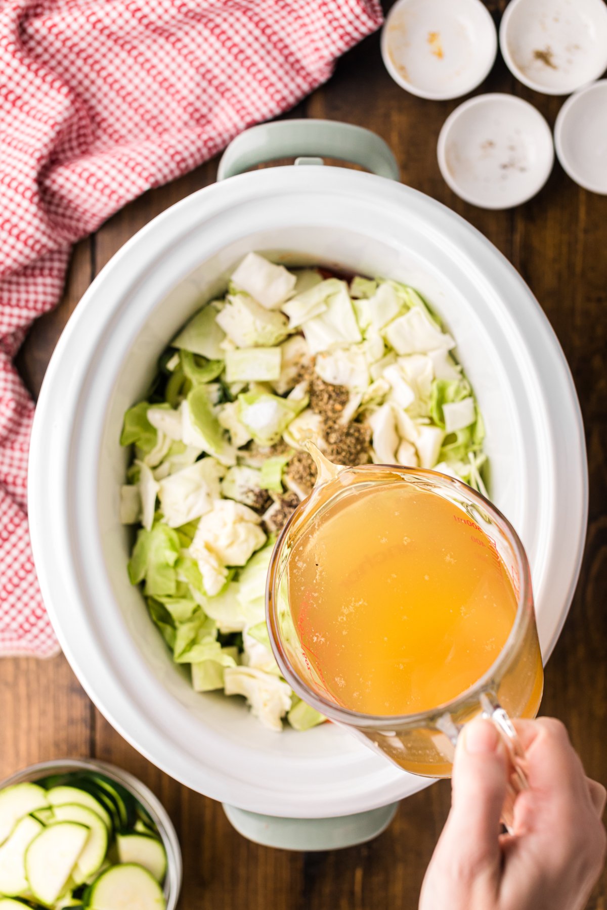 Pouring chicken broth into a crockpot.