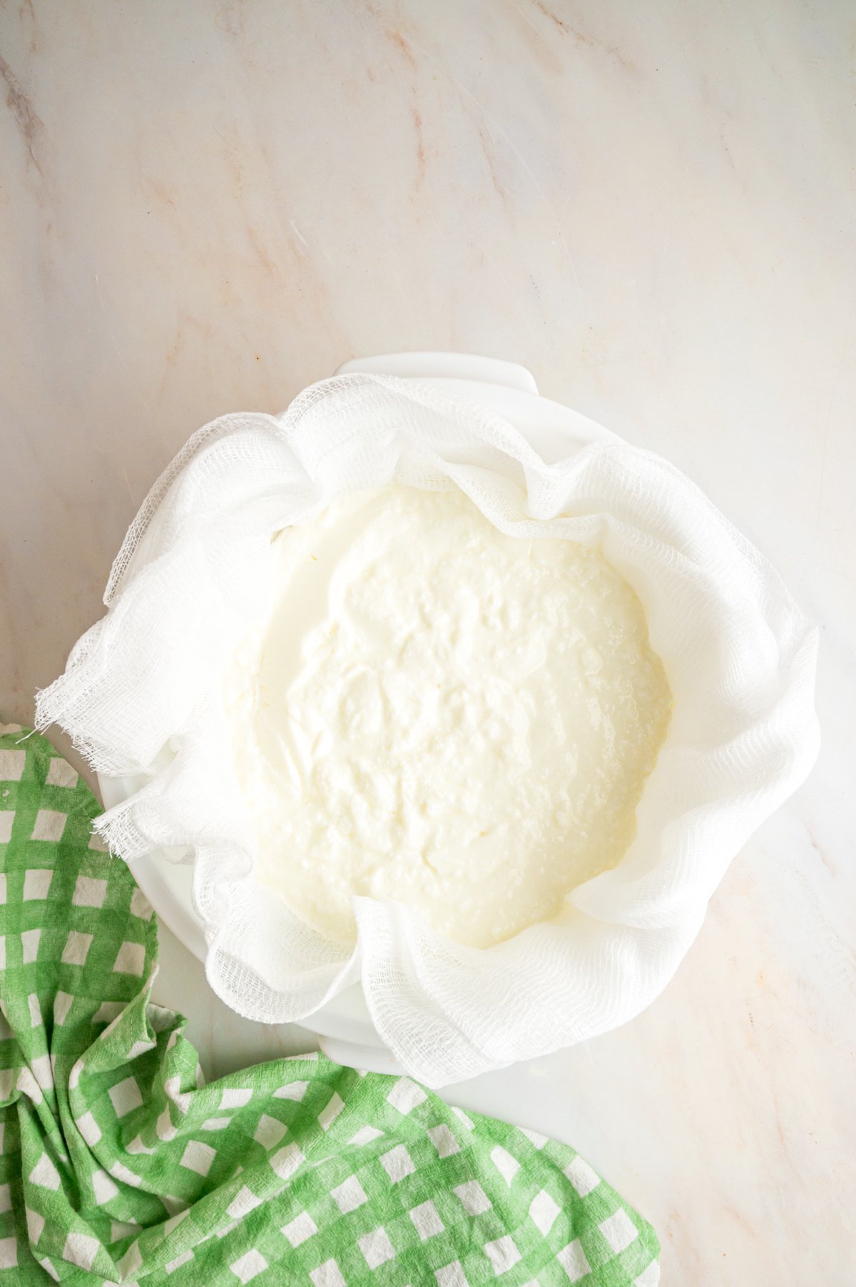 Yogurt straining through a cheesecloth into a bowl.