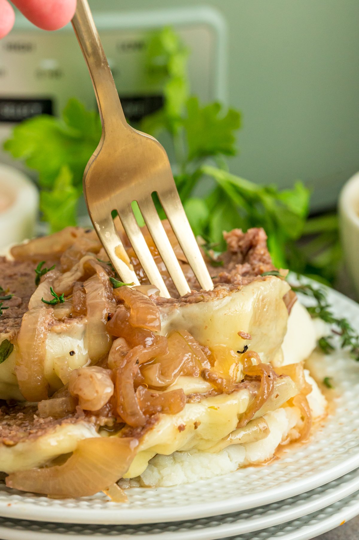 Slow cooker french onion meatloaf on a plate with a fork taking some.