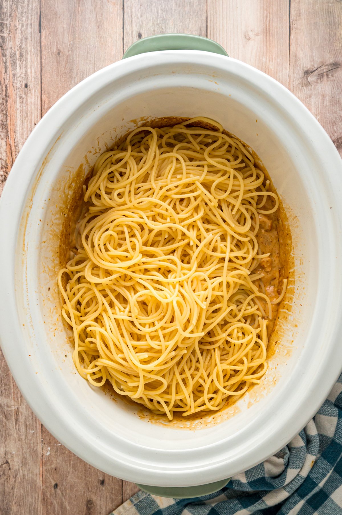 Cooked spaghetti added to a crockpot.