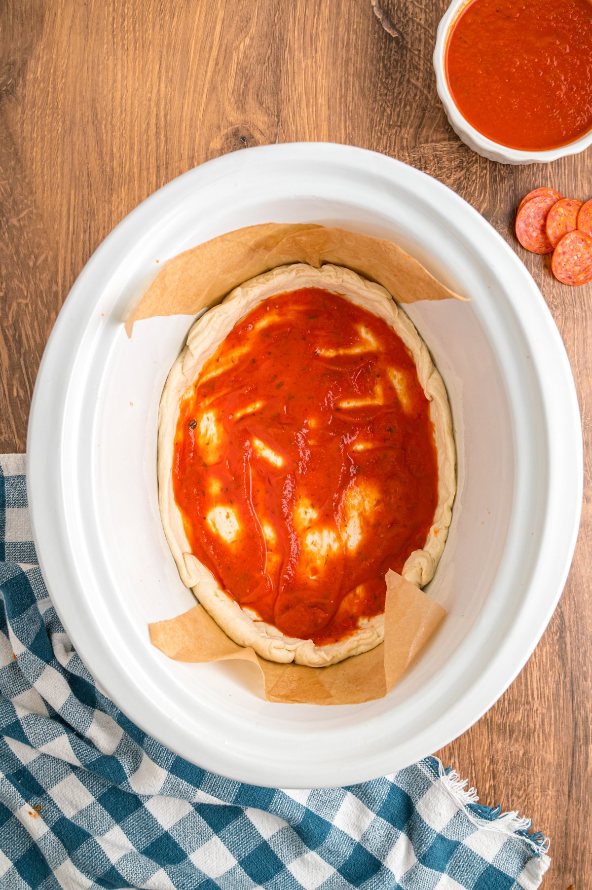 Sauce spread on pizza dough in a crockpot.