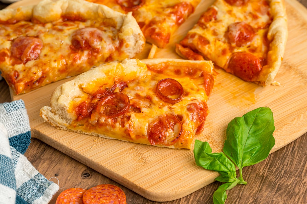 Slices of slow cooker pizza on a wooden board.