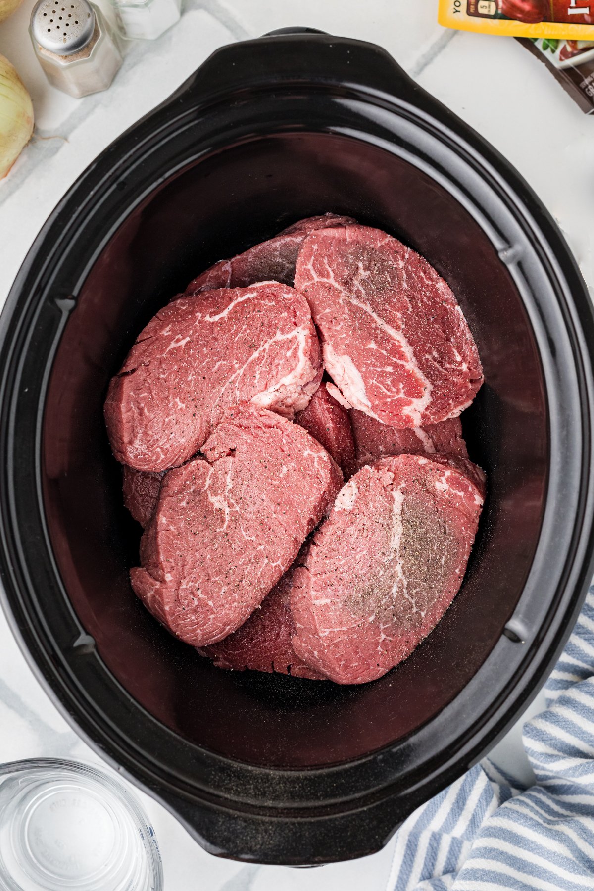 Seasoned steaks in a crockpot.