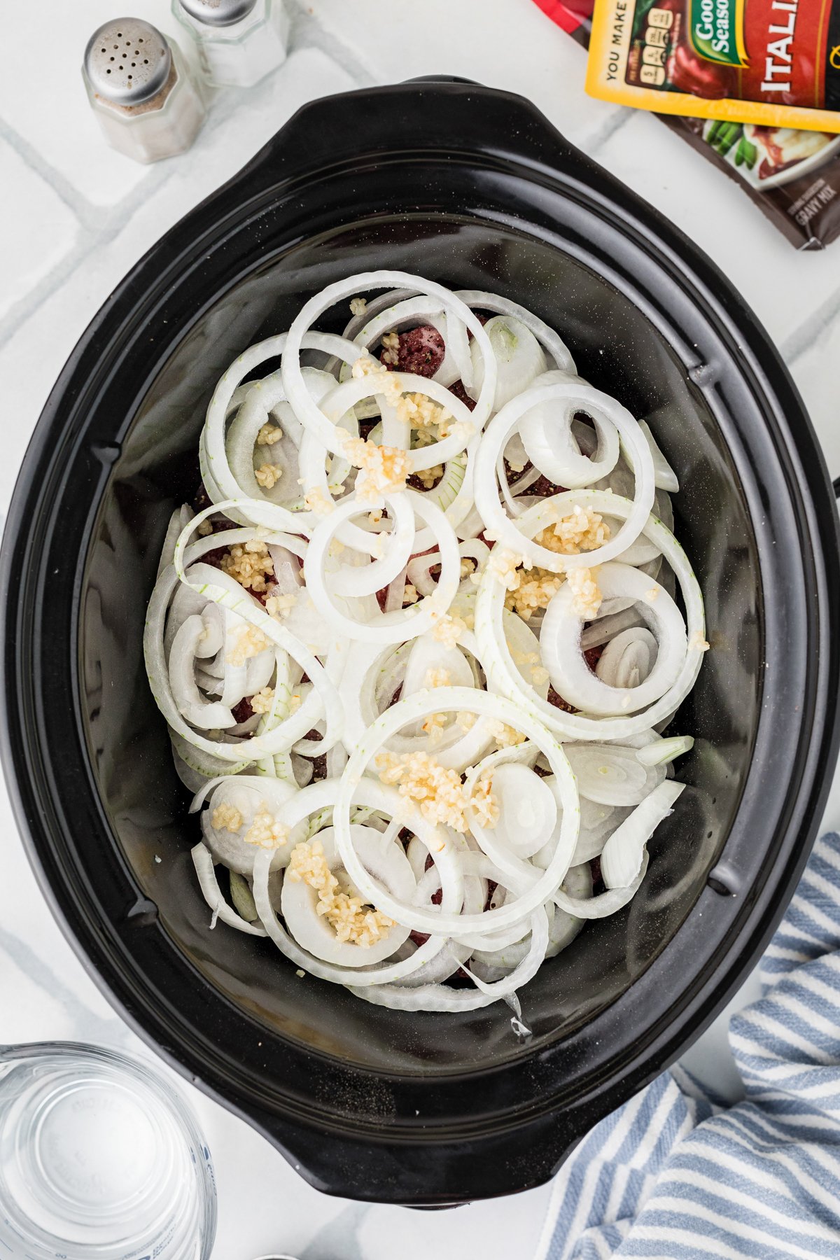 Onions and garlic added on top of steaks in a crockpot.