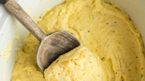 Slow cooker boursin cheese potatoes with a wooden spoon scooping some out.