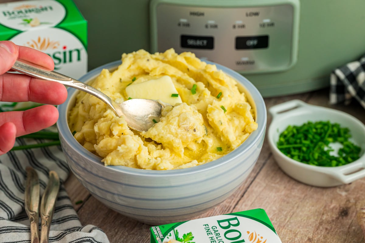 Slow cooker boursin cheese potatoes in a bowl with a spoon.