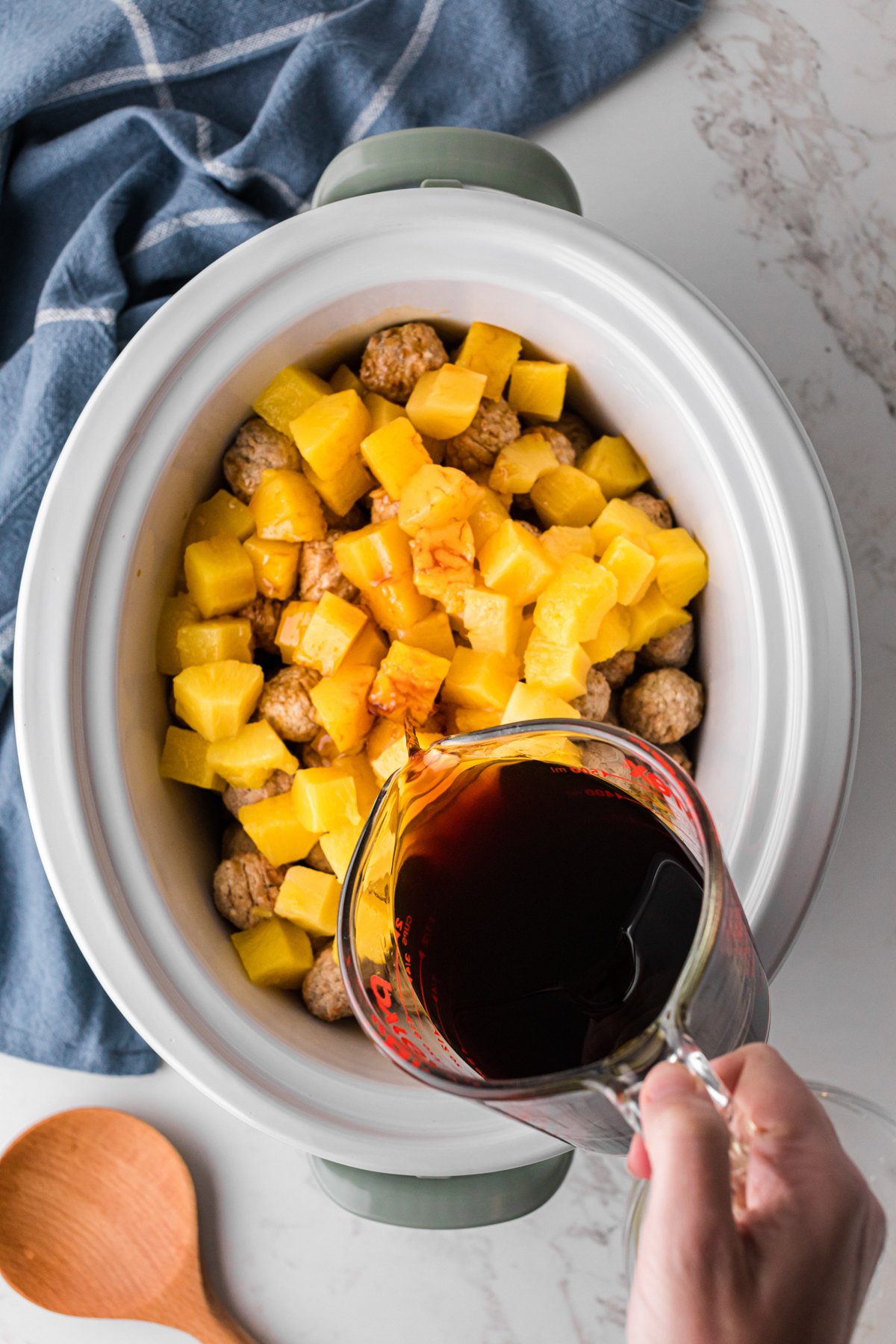 Pineapple chunks and teriyaki sauce added to frozen meatballs in a slow cooker.