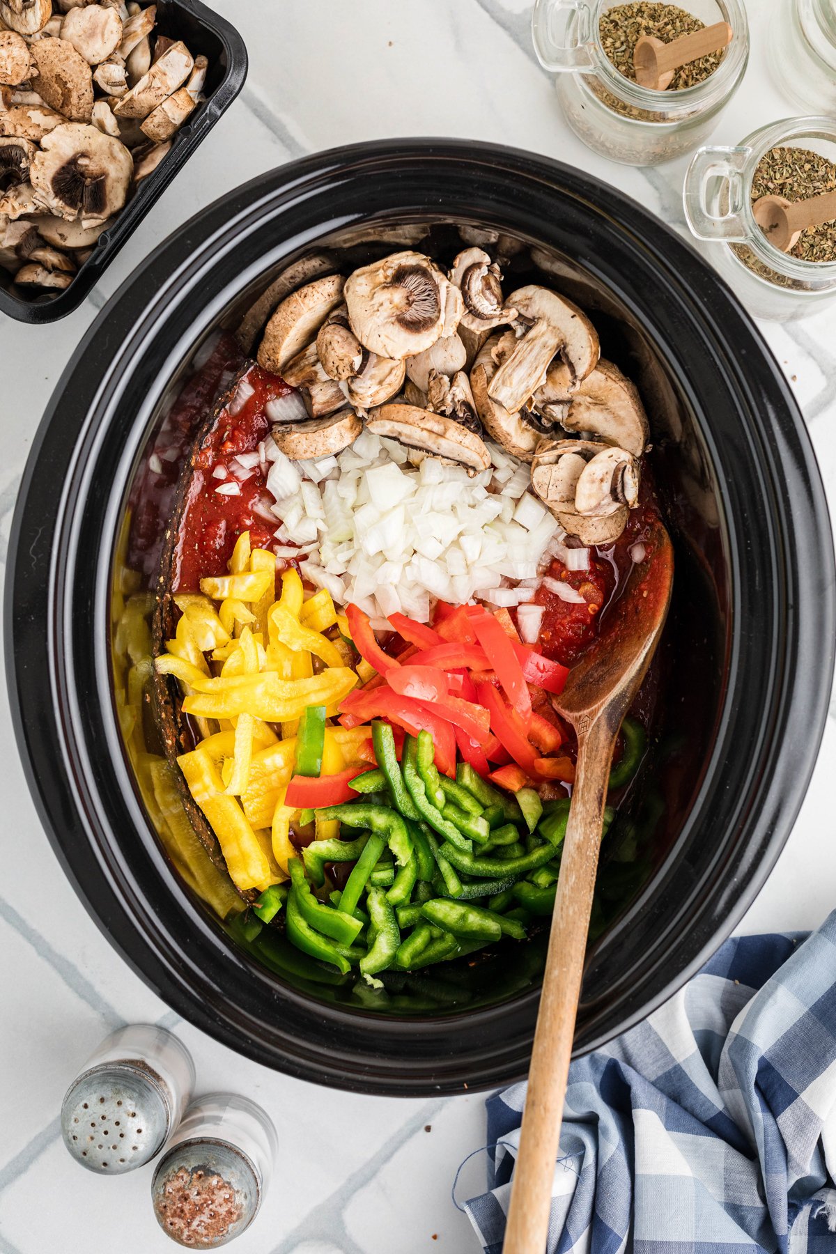 Veggies added to canned tomatoes in a crockpot.