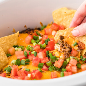 A tortilla chip scooping some slow cooker sunday funday dip.