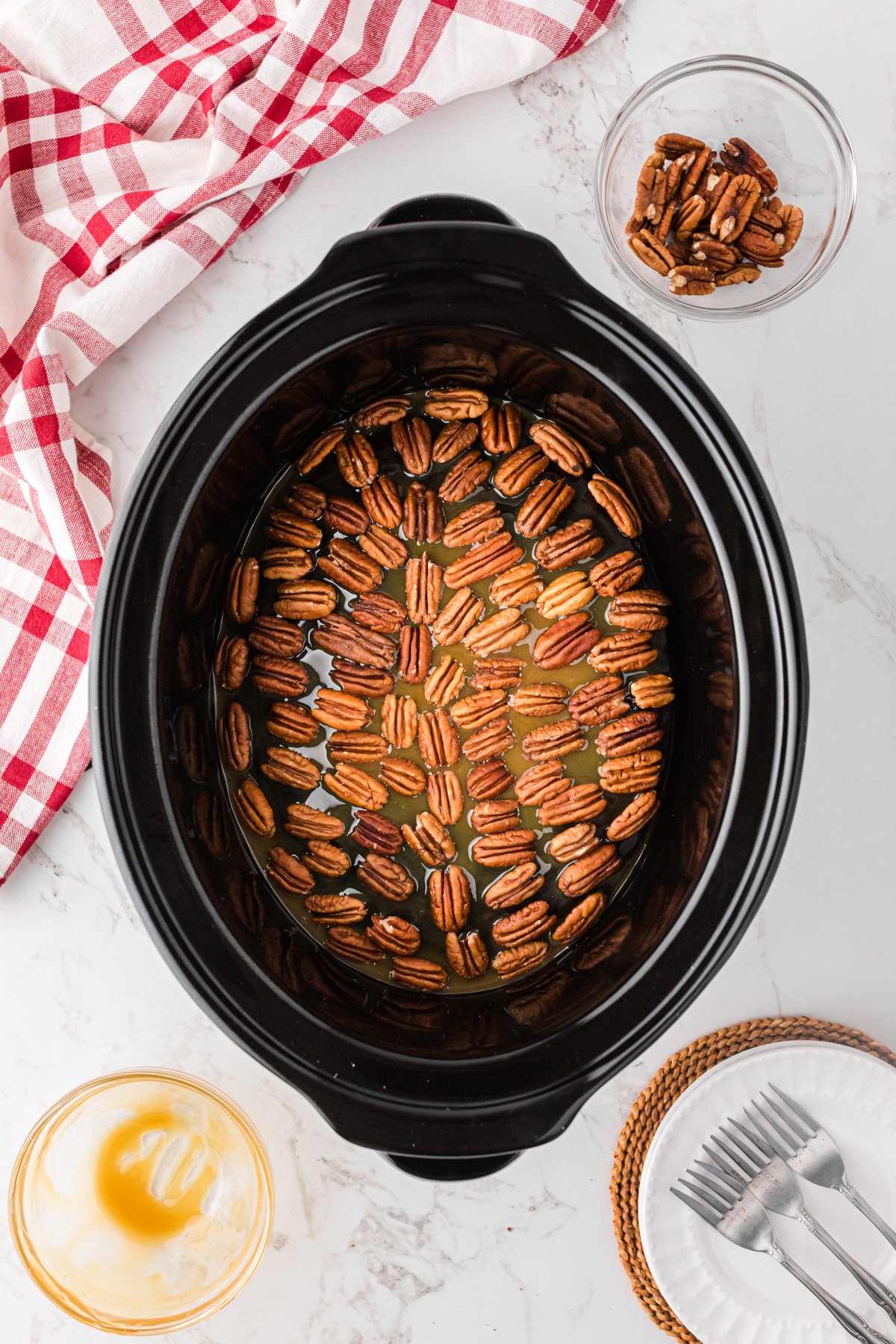 Pecans on top of a cake in a crockpot with caramel on it.