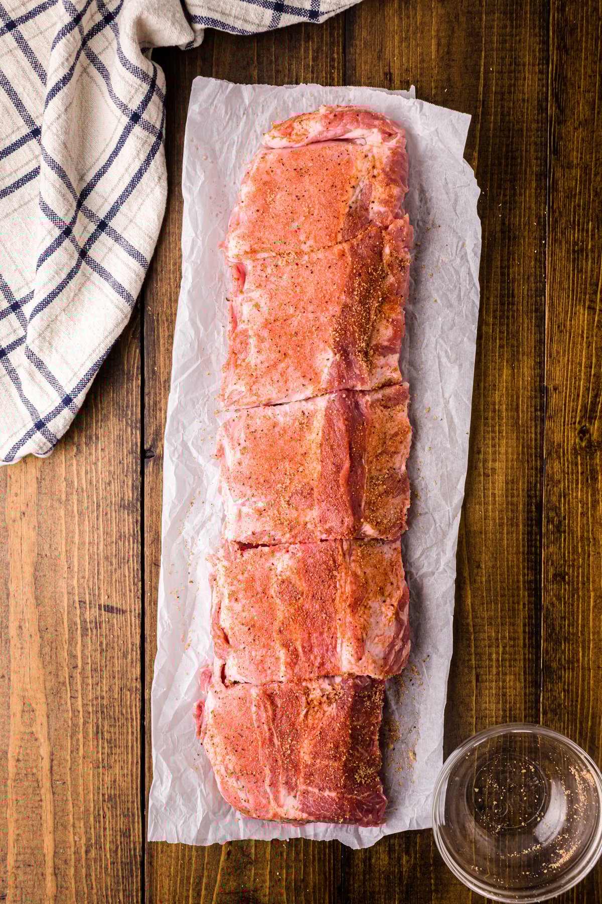Seasoning rub on a rack of ribs separated into four pieces.