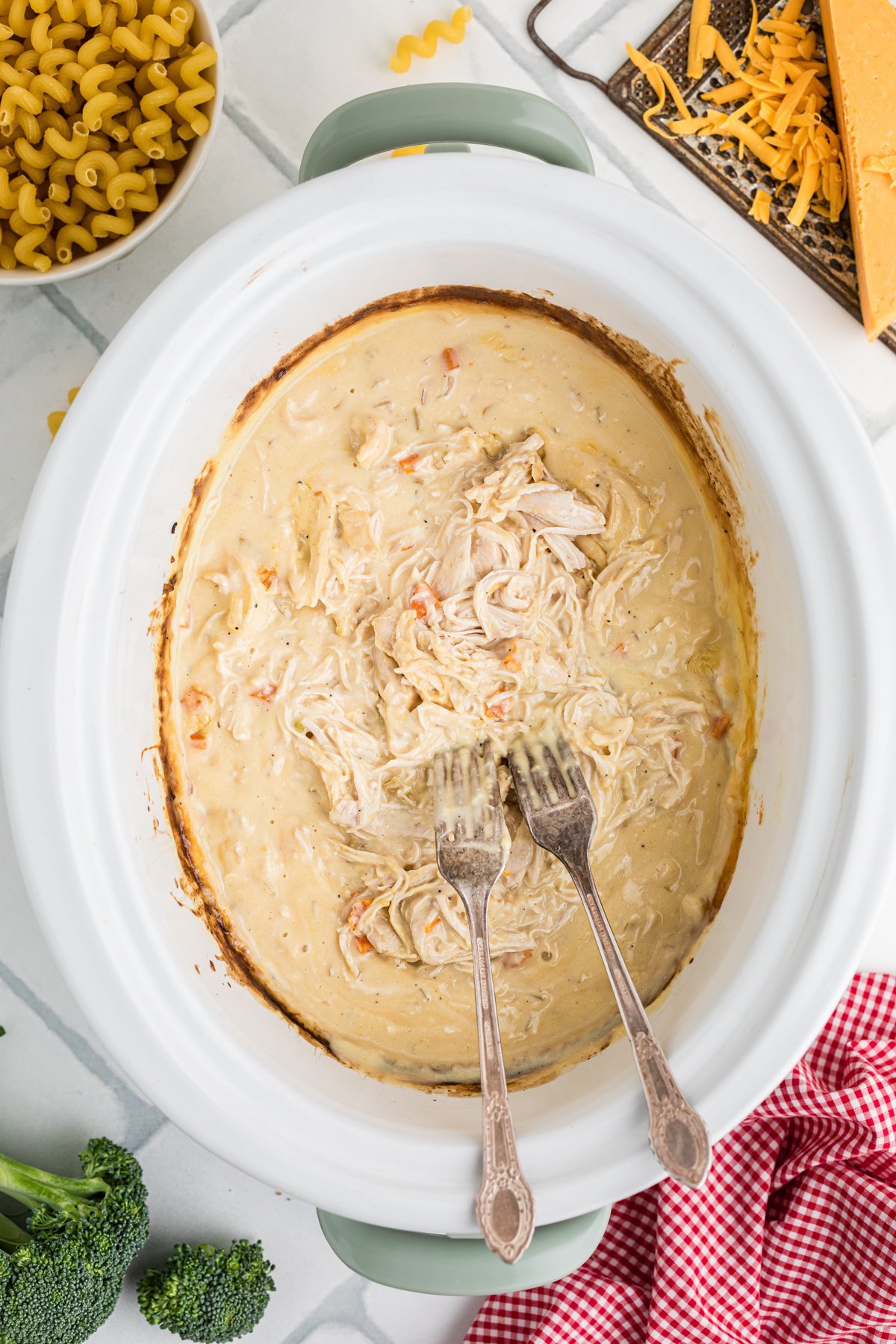 Two forks shredding chicken in a crockpot.