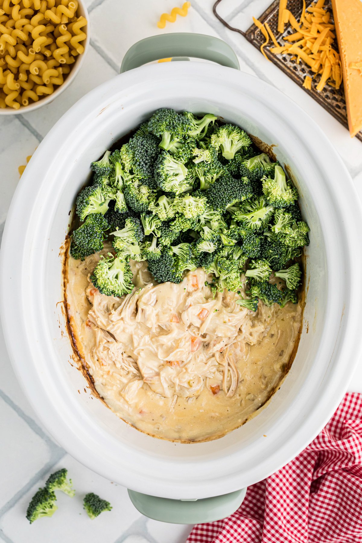 Broccoli added to ingredients in a slow cooker.