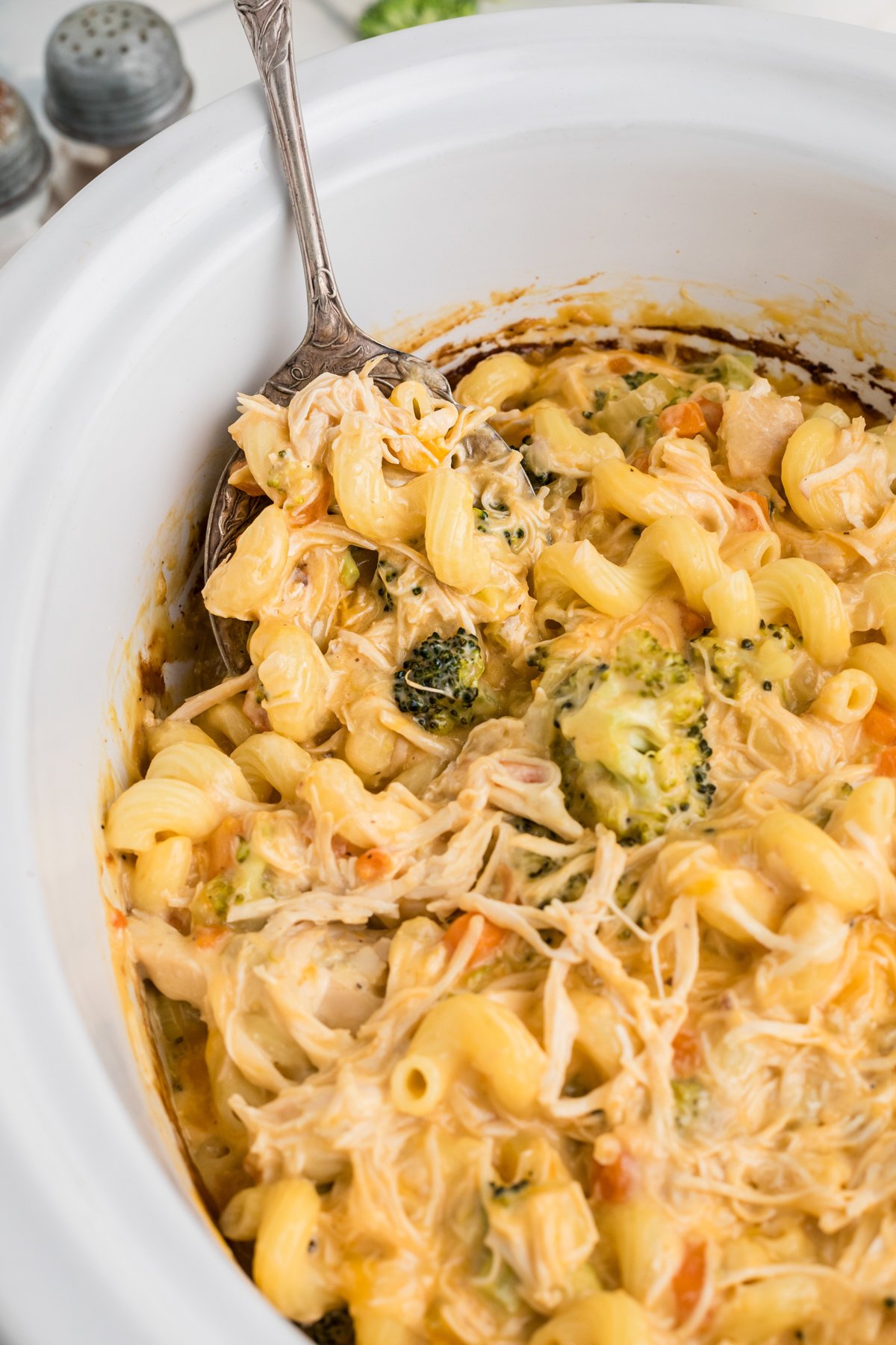 Slow cooker chicken broccoli pasta with a spoon in it.