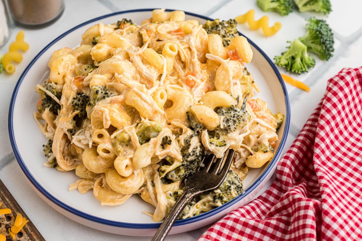 A serving of slow cooker chicken broccoli pasta on a plate with a fork.