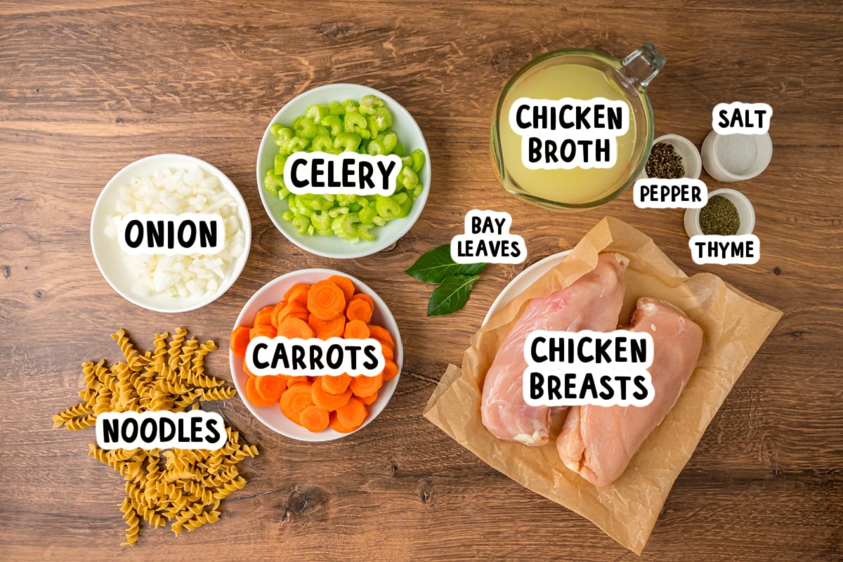 Ingredients for slow cooker chicken noodle soup on a table.