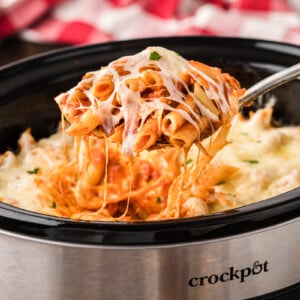 chicken parmesan pasta on a spoon coming from a crockpot.