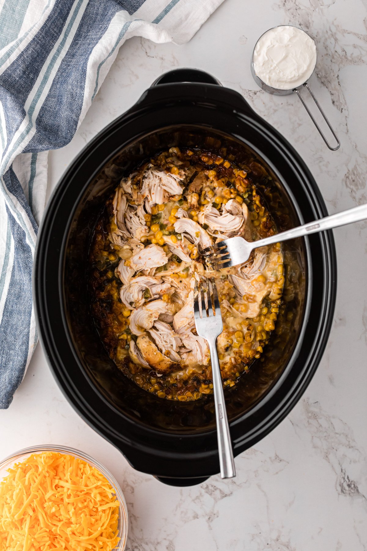 Shredding chicken in a crockpot with two forks.