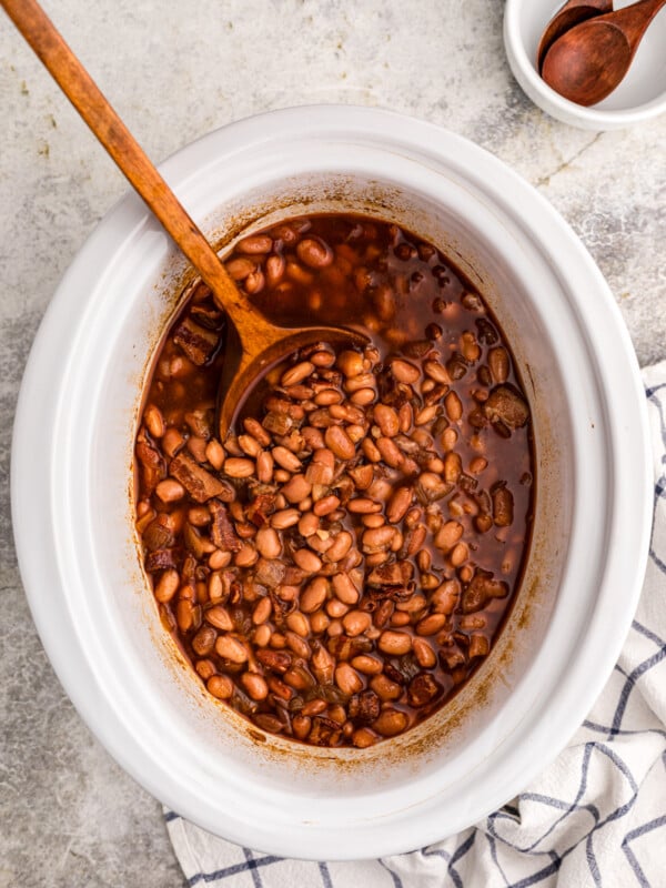 Slow cooker pinto beans with a large spoon in it.