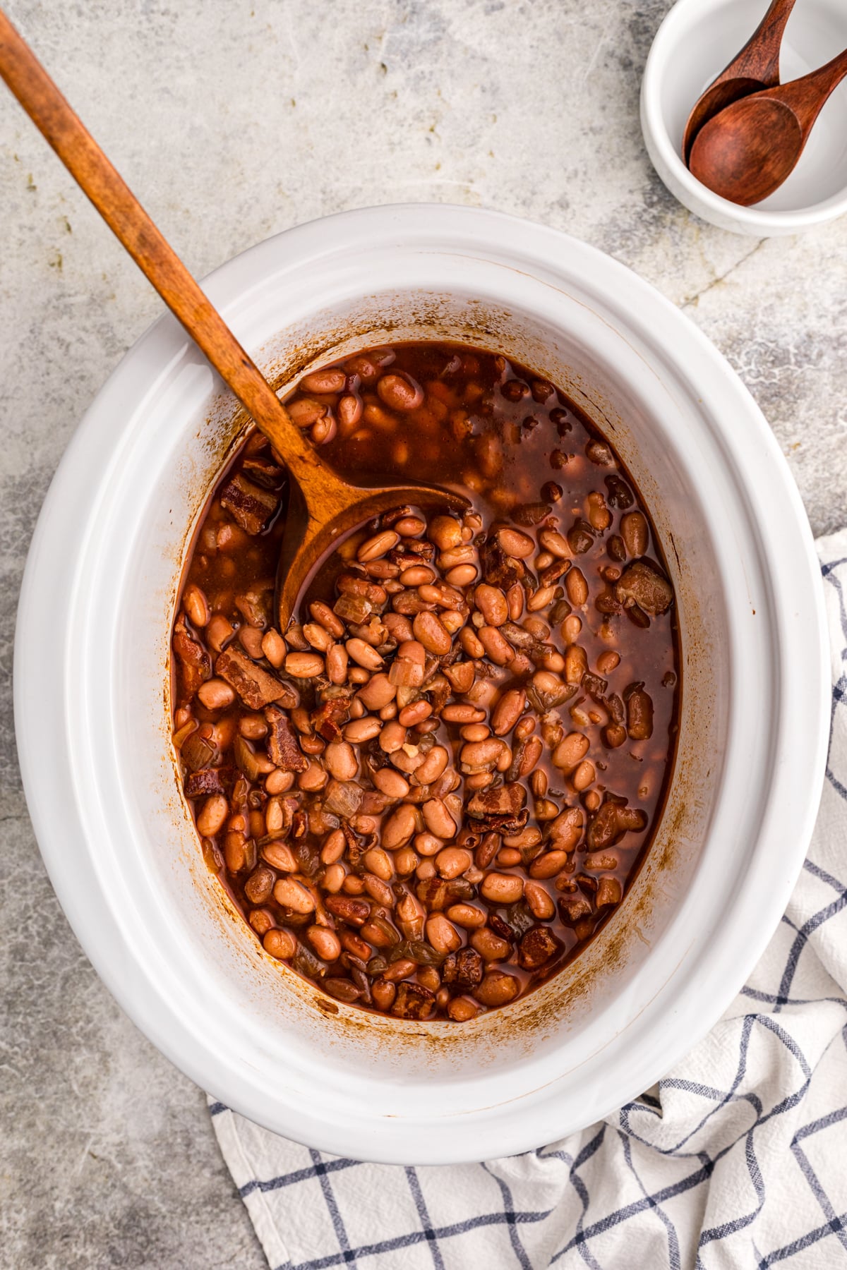 Slow cooker pinto beans with a large spoon in it.