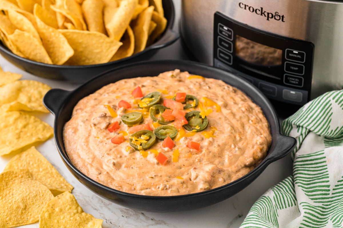 Slow cooker taco dip in a black serving bowl.