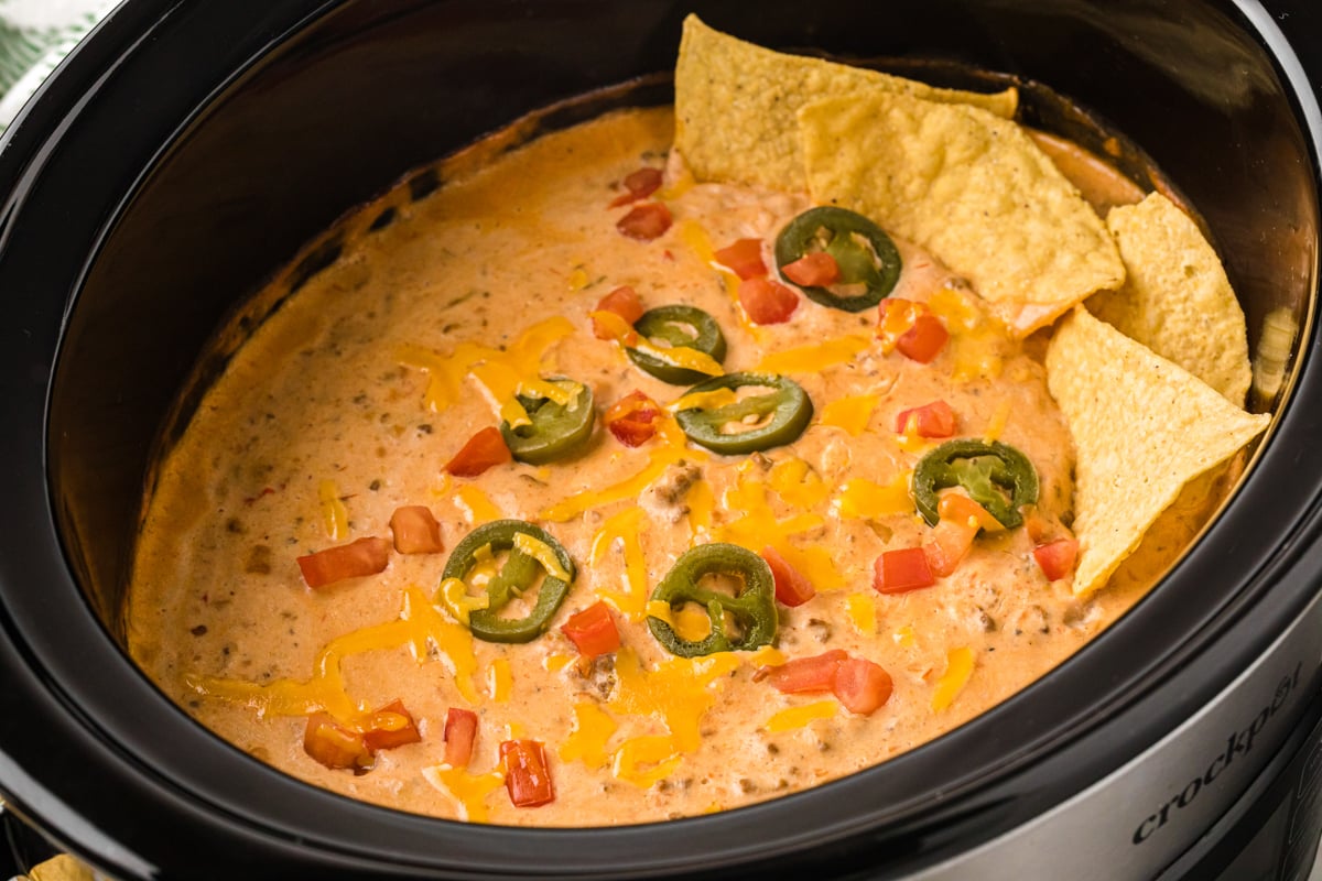 Slow cooker taco dip with tortilla chips and jalapenos as garnish.