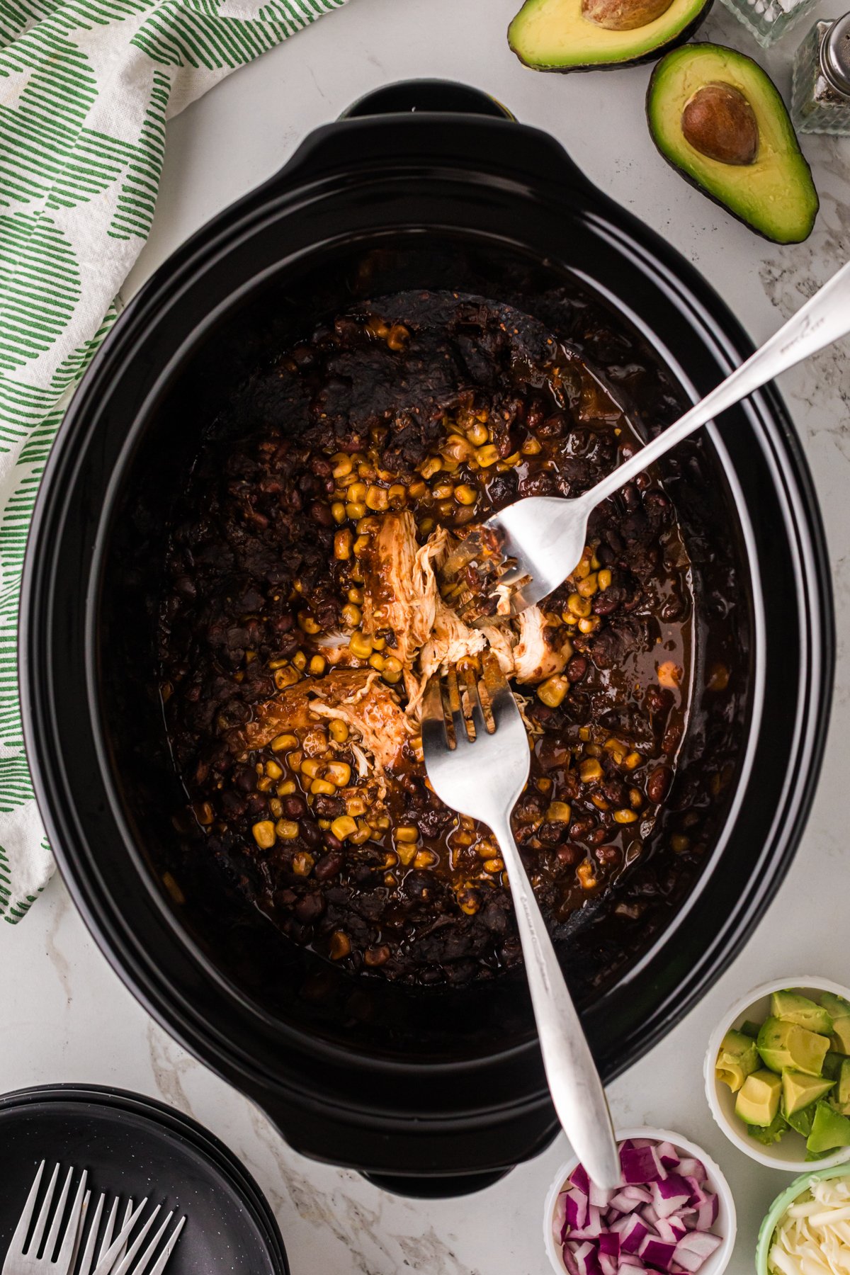 Shredding chicken in a crockpot with two forks.
