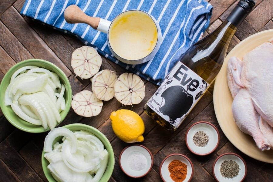 wine, seasonings, butter, onion garlic and lemon on a wooden table.