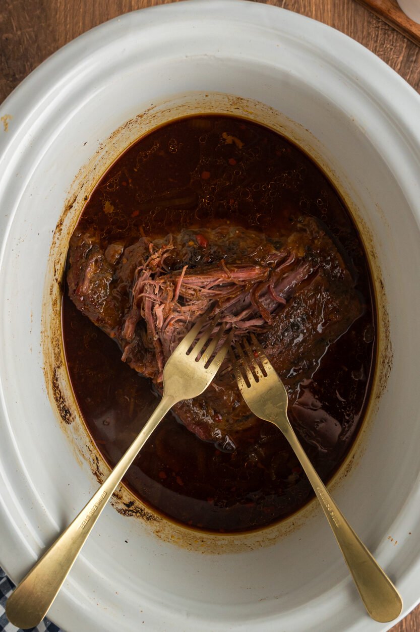 2 forks shredding flank steak.