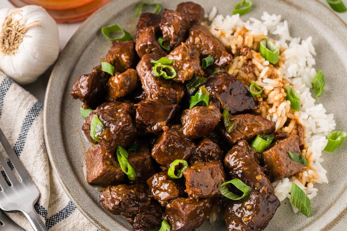 A plate with honey garlic steak bites and white rice.