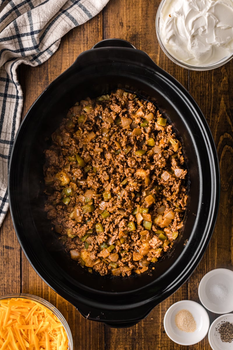 Ground beef on top of tater tots in a crockpot.