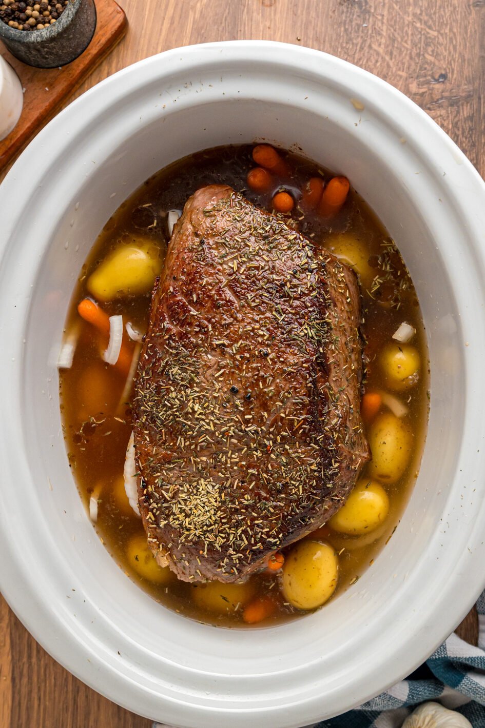 seared rump roast, seasonings, and beef stock added to veggies in crockpot.