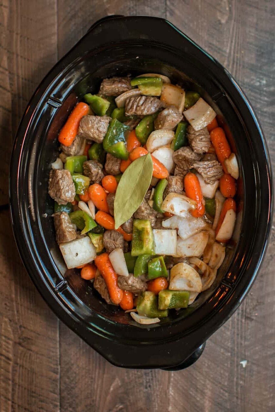 uncooked A1 beef stew in slow cooker with bay leaf on top.