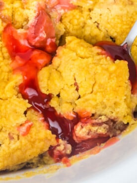 A scoop of dump cake on a spoon about to be taken out of a crockpot.