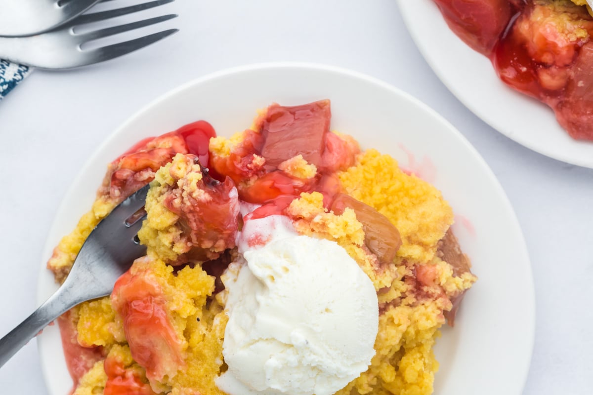 Dump cake on a plate with ice cream on top.