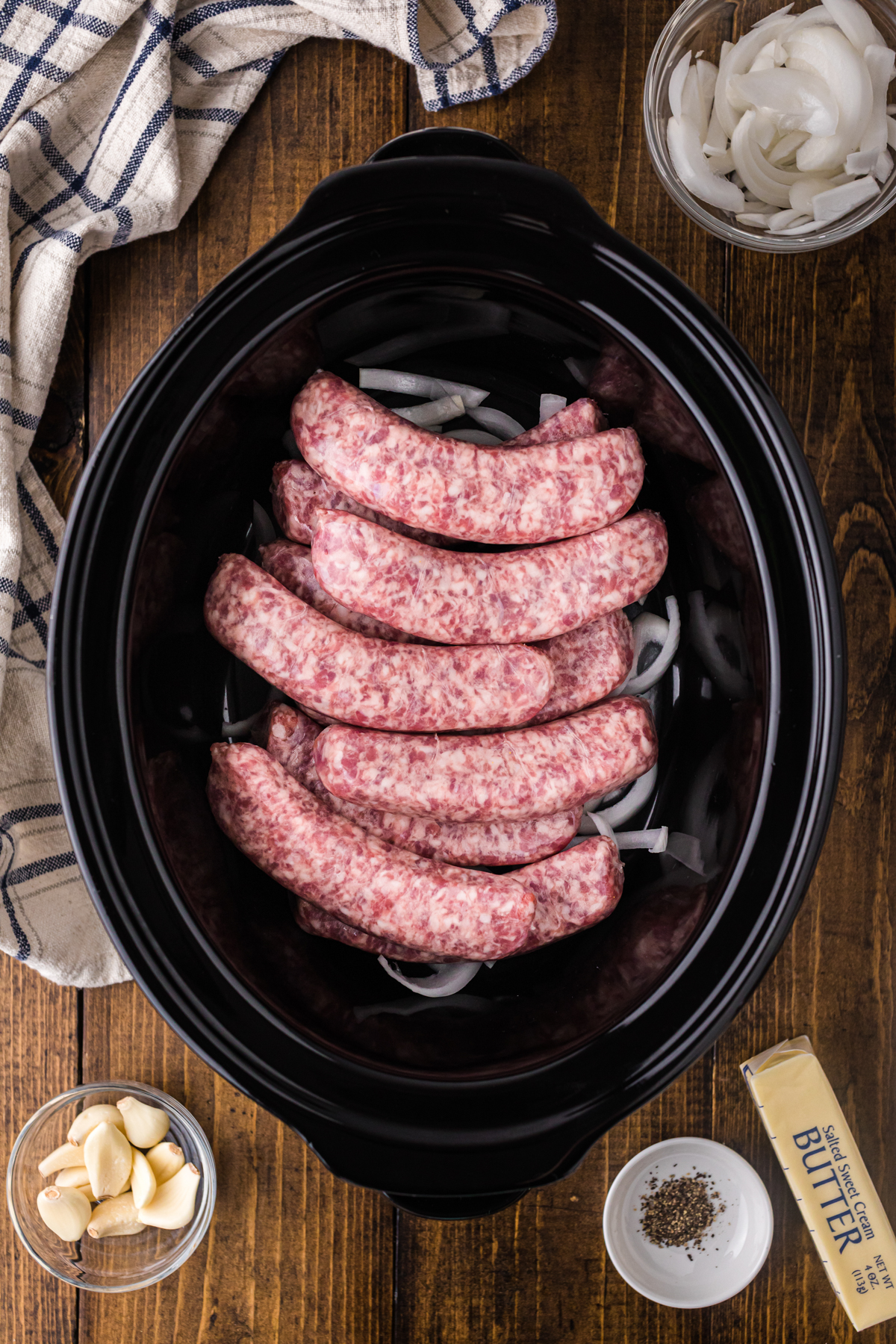 Onions and bratwurst in a slow cooker.
