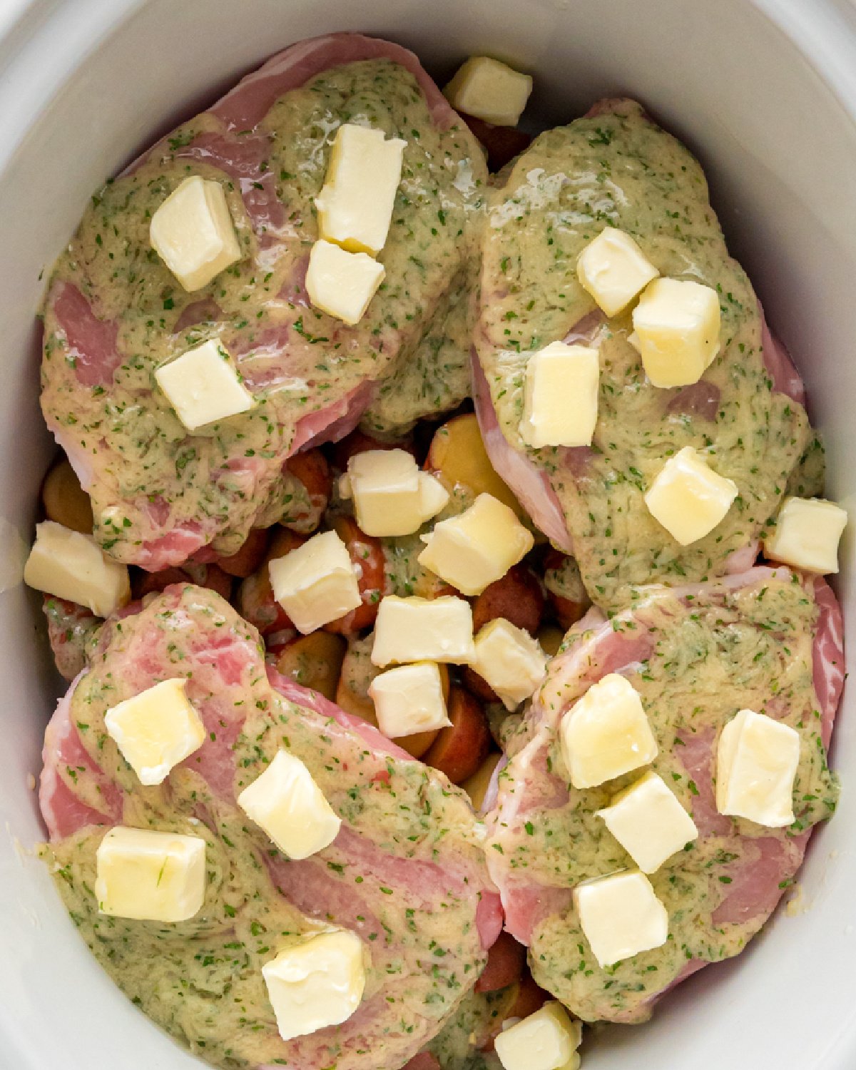 Close up of pork chops with ranch and dots of butter.