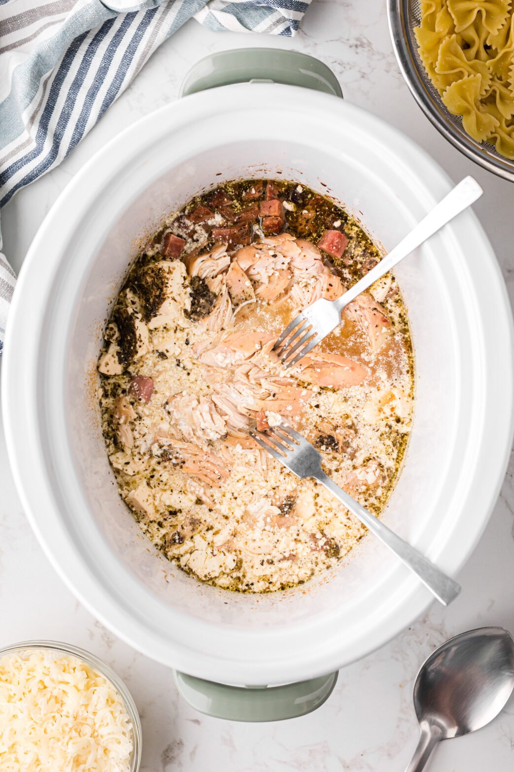 Shredding chicken in a crockpot with two forks.