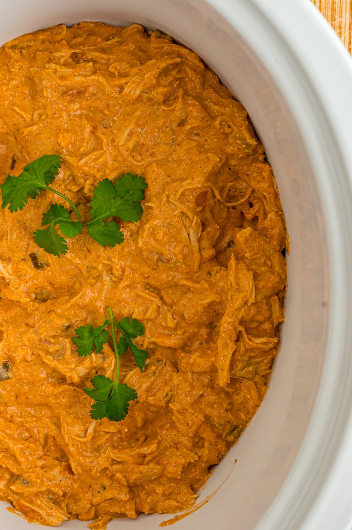 Creamy salsa chicken in a crockpot with cilantro garnish. 
